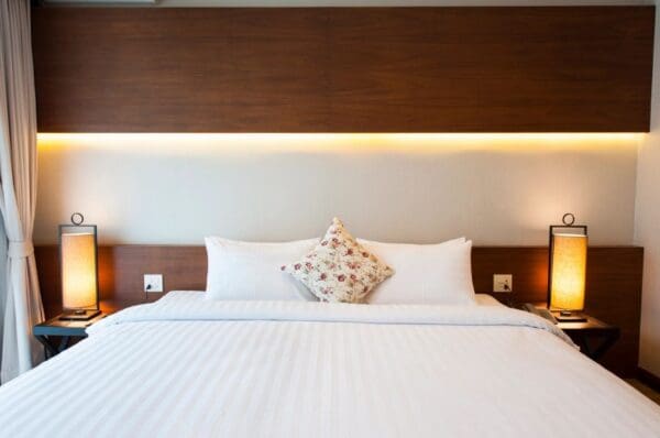 A bed with white sheets and pillows in front of a wall.