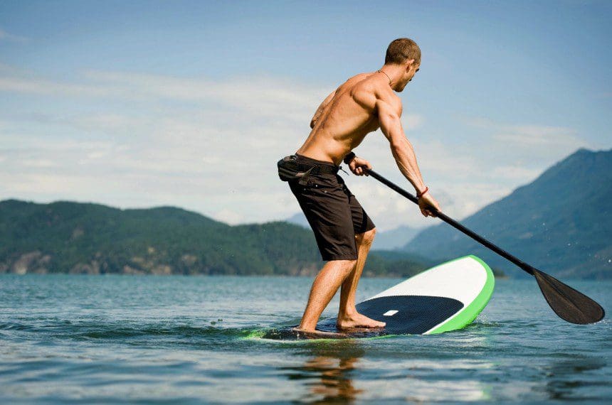 A man is paddle boarding on the water